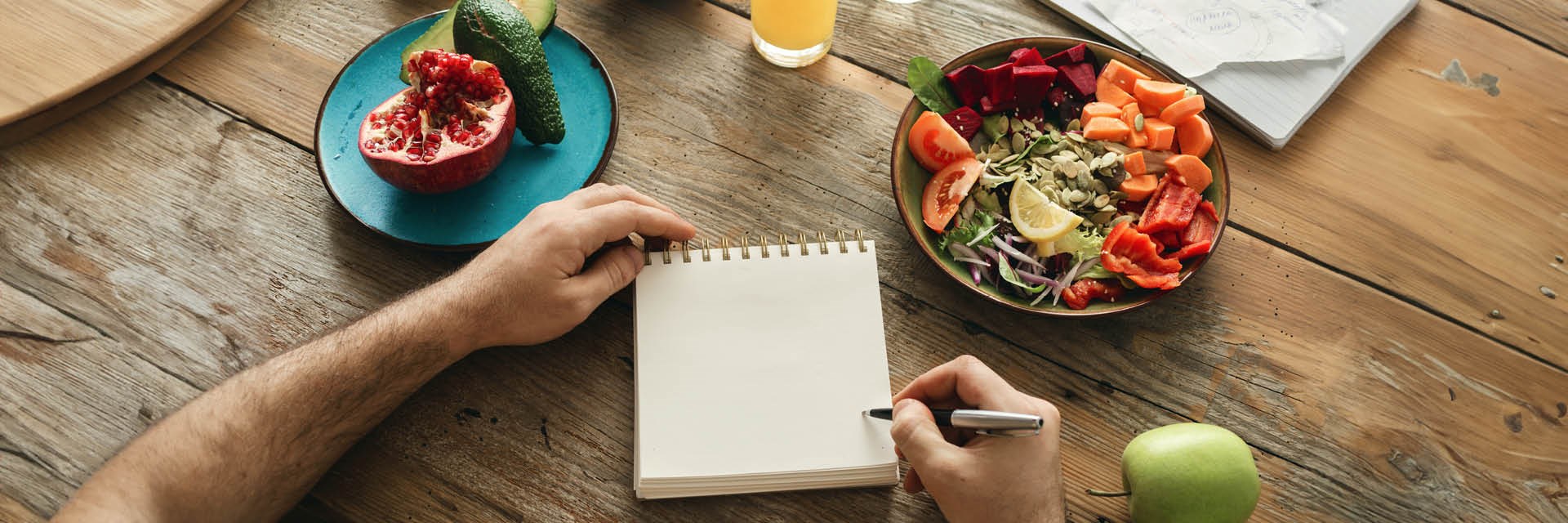 Man writing on a notepad with healthy foods around him