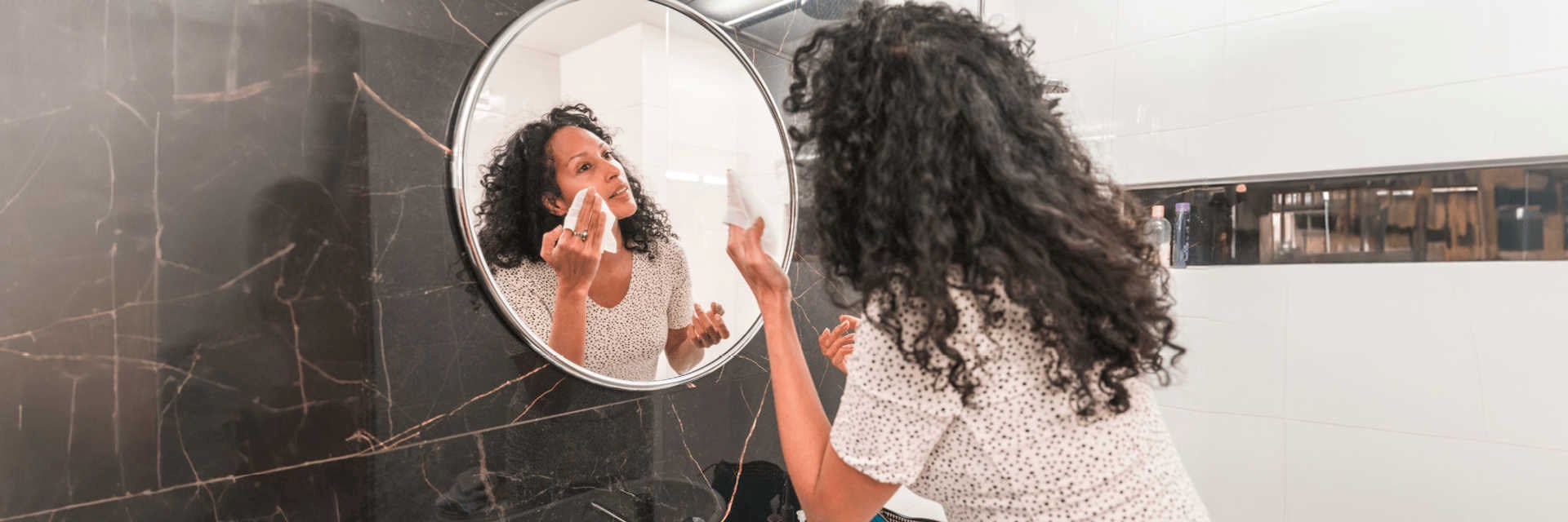 Woman cleansing her face in the mirror