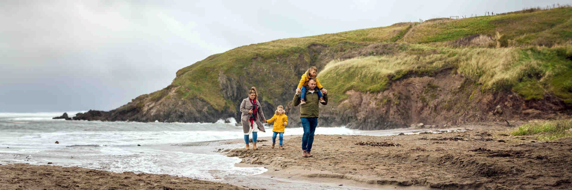 Family walking along a beach by a headland