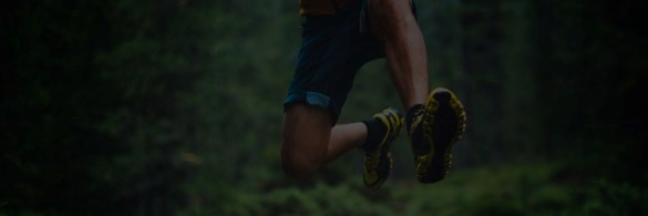 Person in running gear jumping in the woods