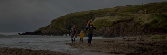 Family walking on the beach near a cliff