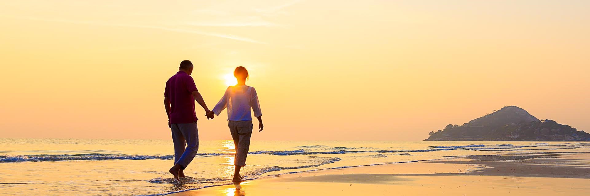 A couple holding hands on a beach in the evening