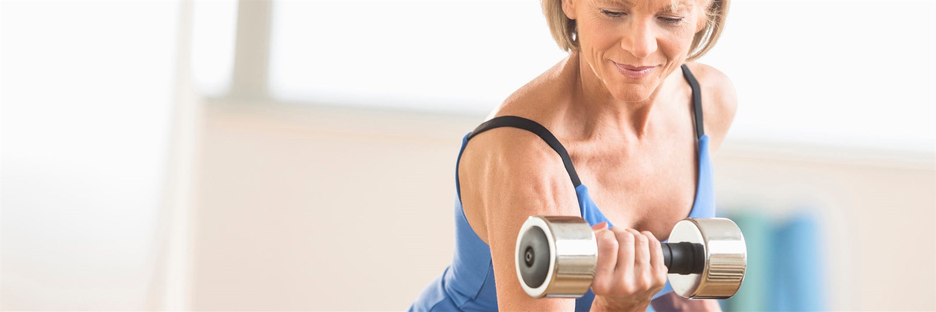 Fit middle-aged woman lifting weights at home