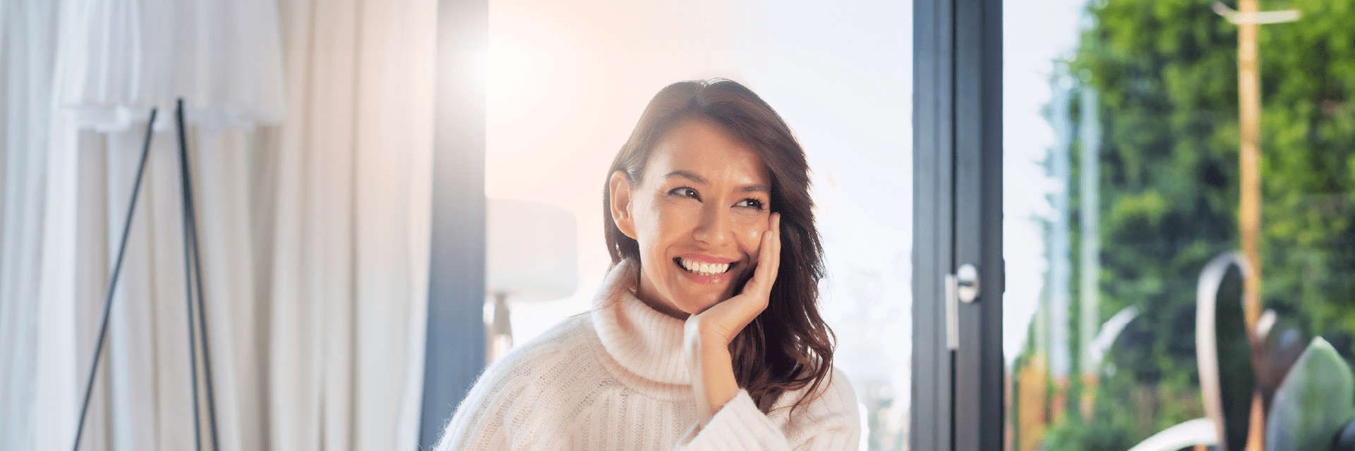 Woman in cream jumper smiling with glowing skin