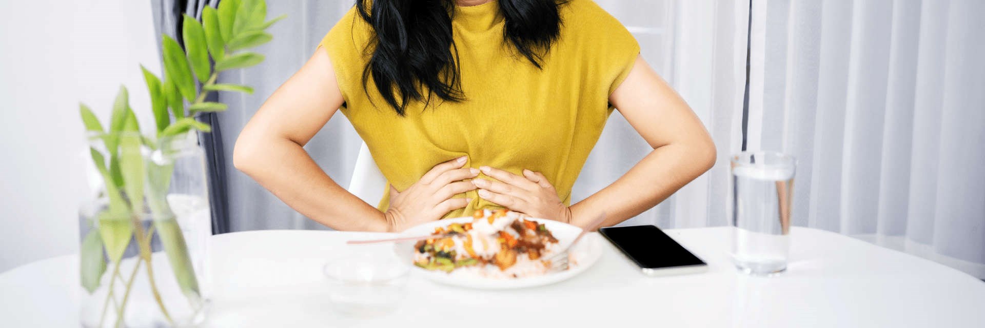 Woman eating a meal holding her stomach in discomfort