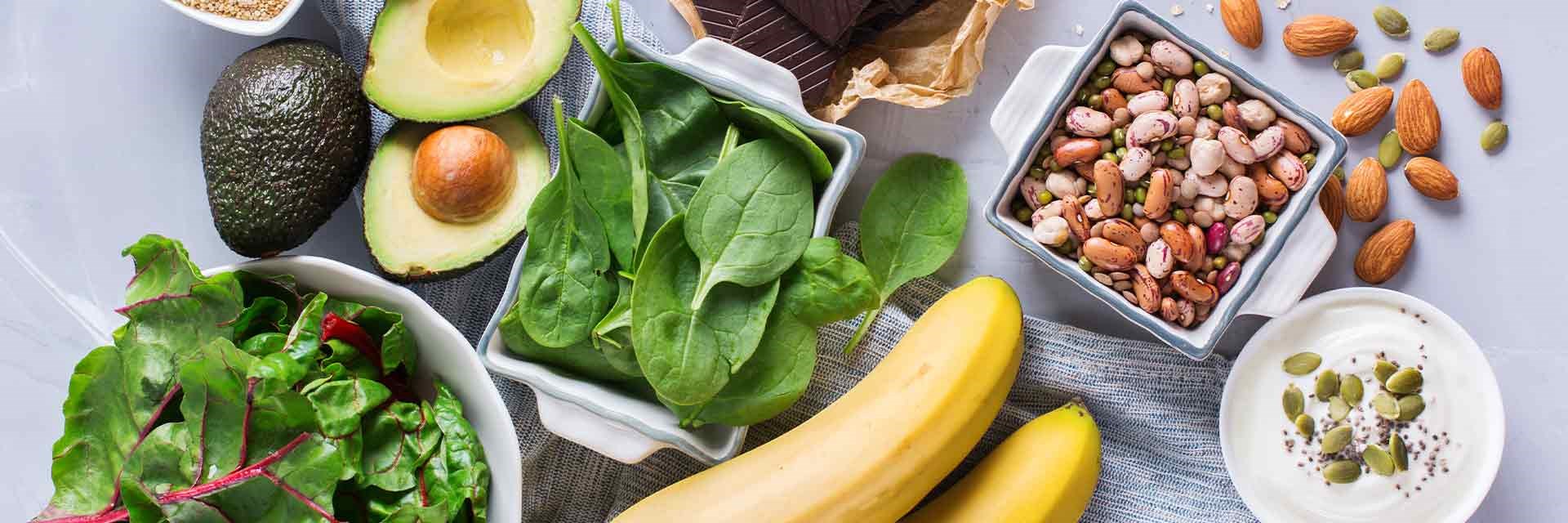 An overhead photo of magnesium rich food, including avocados, spinach and bananas