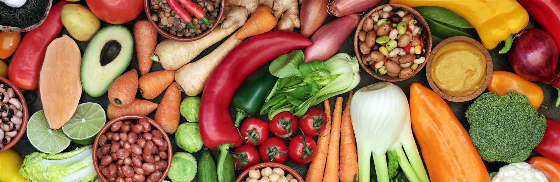 An overhead photo of a range of colourful vegetables and nuts, including carrots, peppers, potatoes and avocados