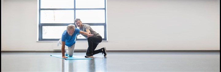 Man doing exercise while someone helps him