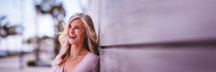 Image of an elderly woman laughing by a wall