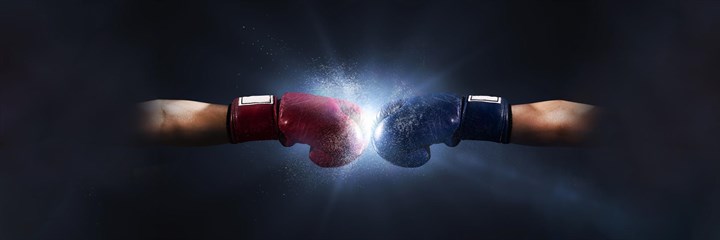 Red and green boxing gloves clashing together