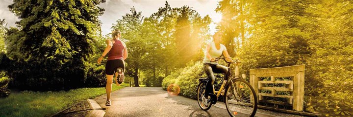 A runner and a cyclist on a lane in the sunshine