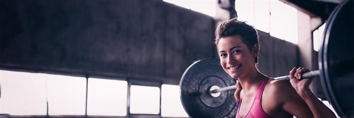 A smiling woman lifting weights