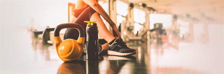 A woman sat down with a kettle bell in a gym