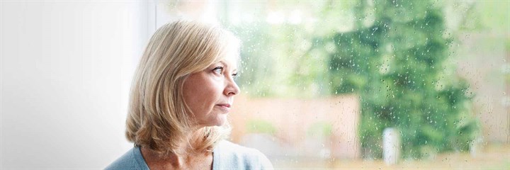 A worried-looking woman looking out of the window