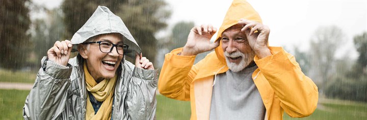 A mature woman and man stood in the rain laughing