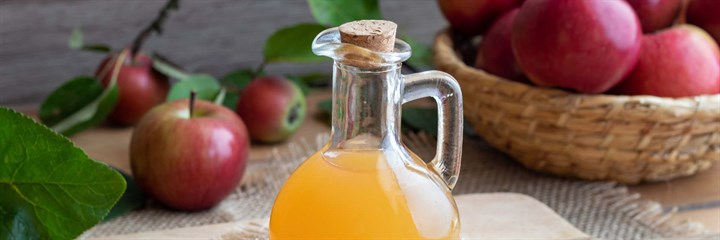 Bottle of apple cider vinegar with apples in the background