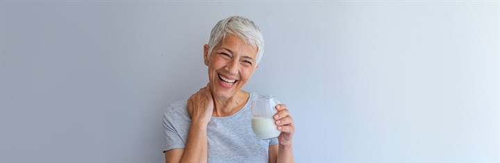 Mature woman with short grey hair laughing with a glass of milk
