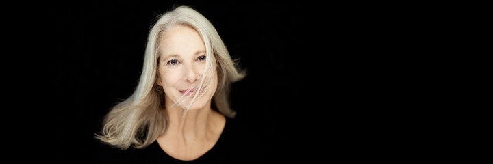 Middle-aged woman with blond hair across face looking at camera