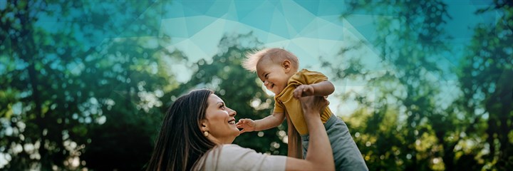 Smiling woman holding up her baby