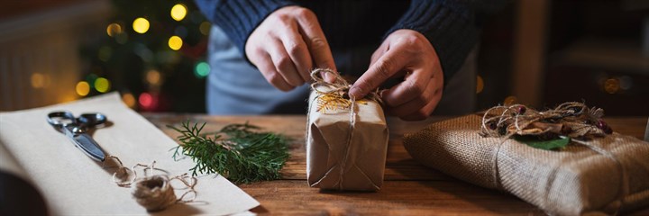 Person tying up string on presents wrapped in brown paper