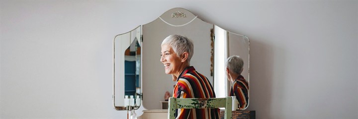 Woman sitting in front of dressing table and mirror