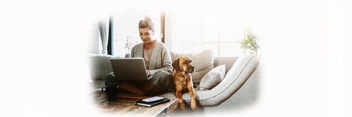 Woman sitting on sofa with her laptop and dog