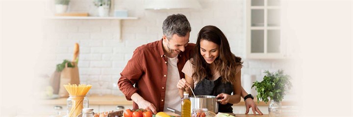 Man and woman smiling and cooking