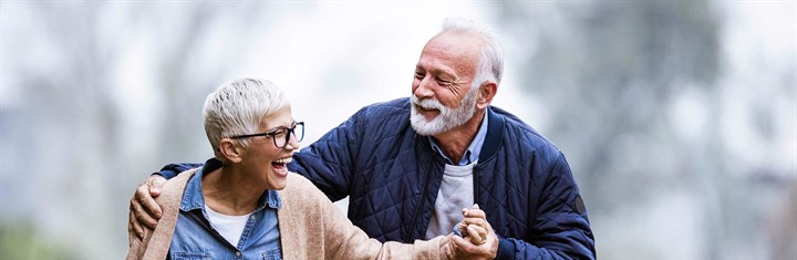 Older couple laughing and hugging outside