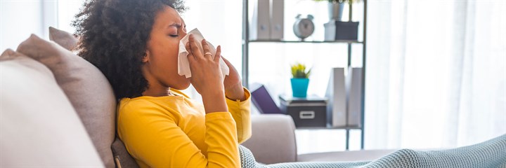 A woman sneezing into a tissue