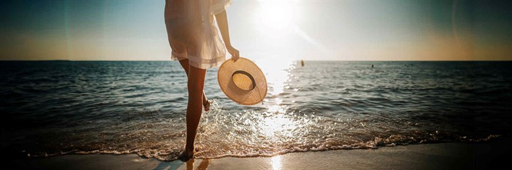 Young woman splashing her foot in the sea in the evening sun