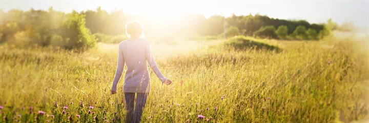 A woman walking through a field in the sunshine