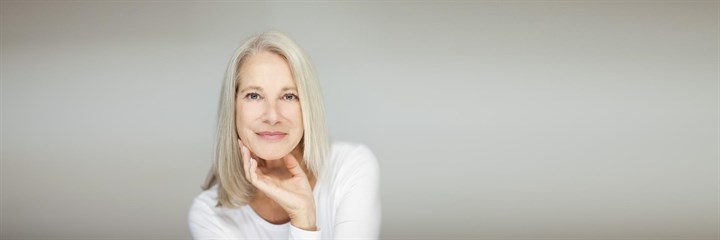 Middle-aged woman smiling and resting chin on hand