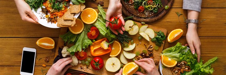 Three people sharing a large plate of vegan food