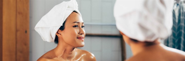 Woman with towel on her head looking in the mirror