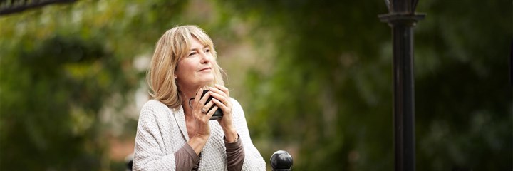 A middle-aged woman with a cup of tea in a garden