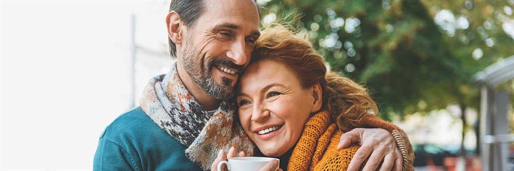 Couple embracing holding cups of coffee
