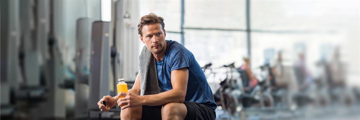 A man sitting down at the gym with a drinks bottle