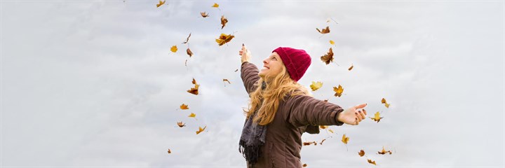 Woman smiling surrounded by autumn leaves
