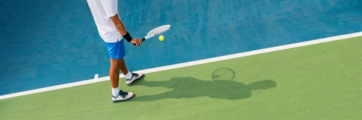 Person bouncing ball on racket on tennis court