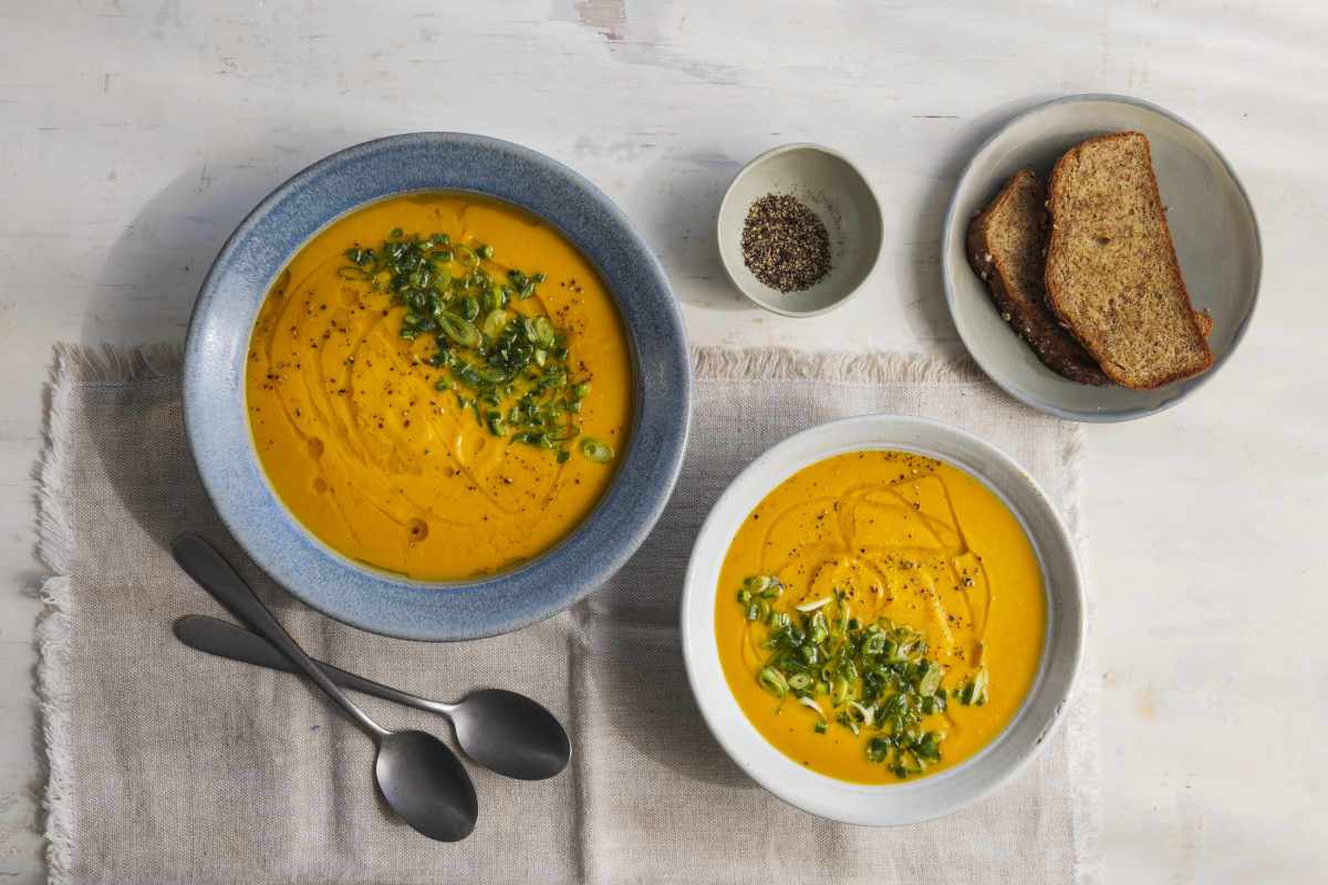 Carrot and turmeric soup in bowls with bread