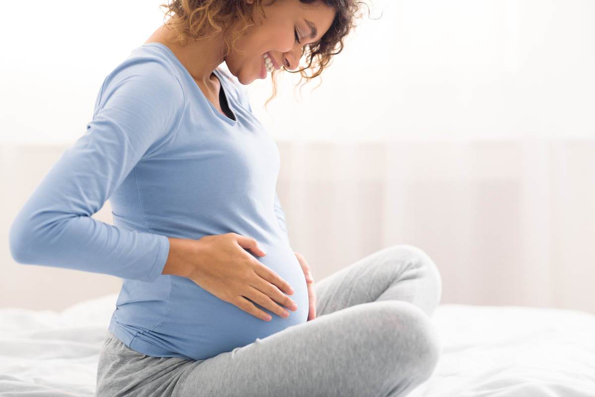 Pregnant woman holding her bump and smiling
