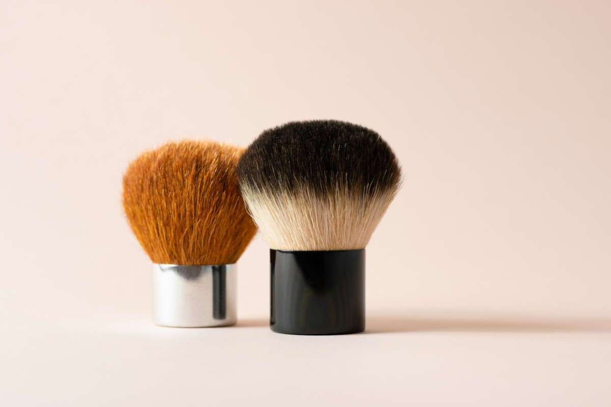 Two makeup brushes on a beige background