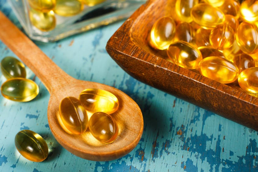 Cod liver oil capsules on wooden spoons