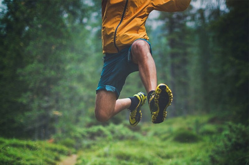 Man in running shoes jumping in the forest