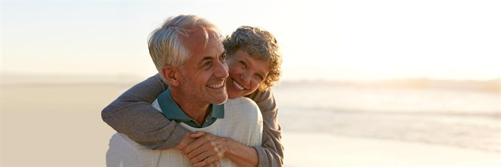 Image of an elderly couple on the beach smiling