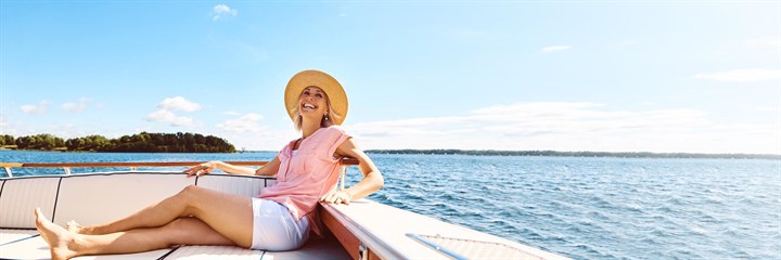 A woman sat on a boat smiling with a view behind her