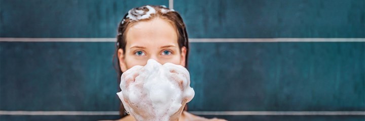 Woman in the shower with bubbles in her hand