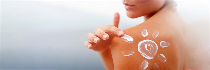 Image of sun cream in the shape of the sun on a woman shoulder
