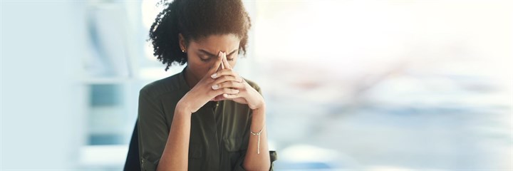 Woman with hands folded on her face looking stressed