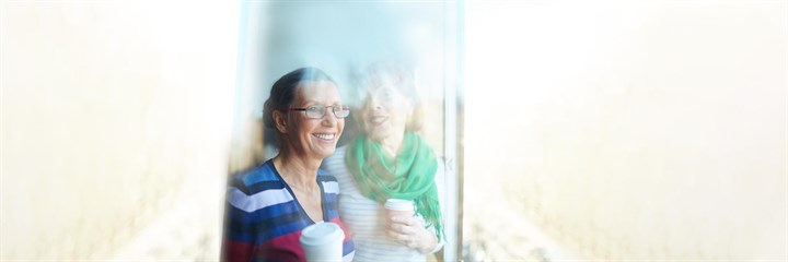 Two women looking out a window smiling